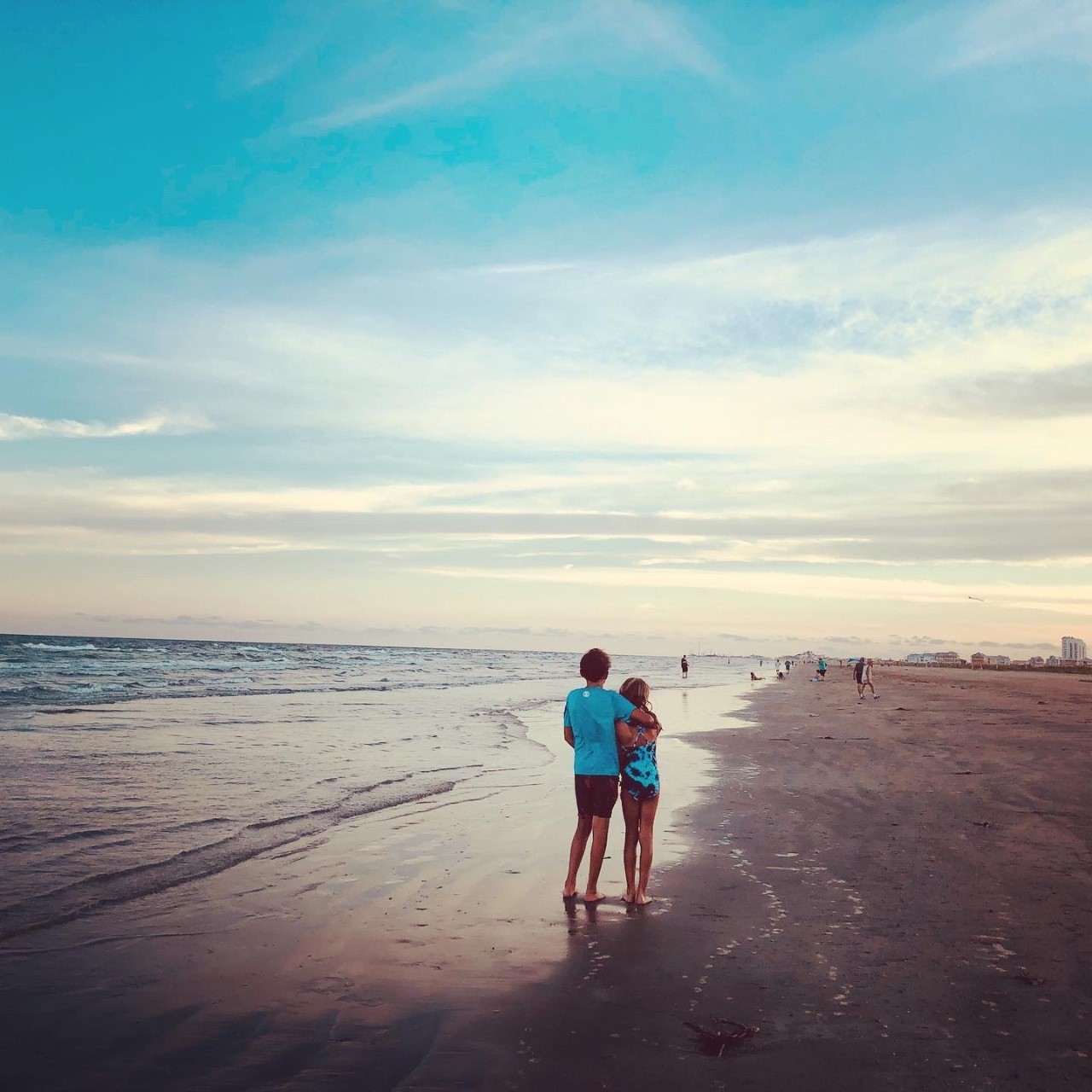 Couple embracing on a serene beach at sunset.