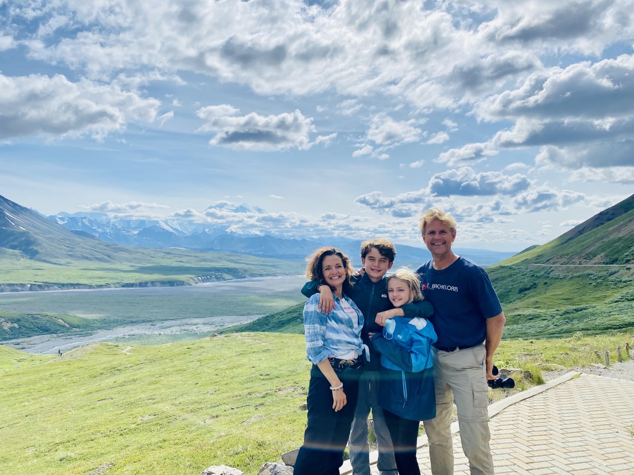 Family enjoying a scenic mountain view under a partly cloudy sky.