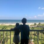 Two children looking out over a beach from a balcony.